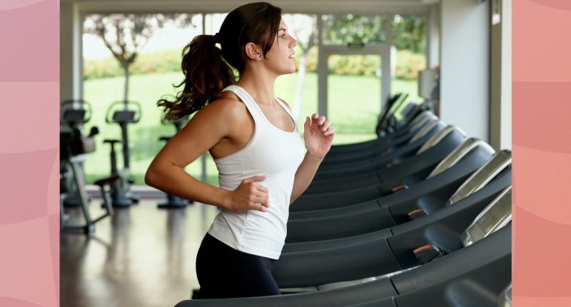 fit brunette woman running on treadmill in front of windows at the gym