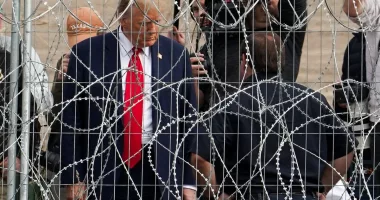 Trump waves at migrants through barbed wire fence at Mexican border