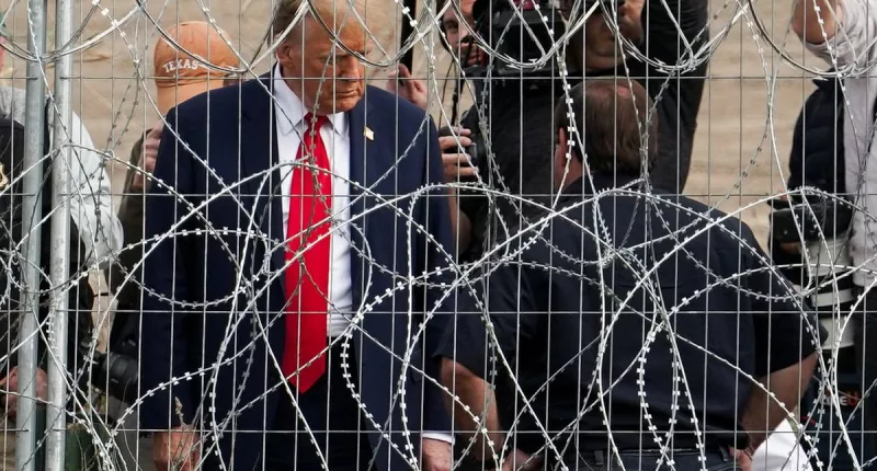 Trump waves at migrants through barbed wire fence at Mexican border