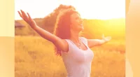happy woman with curly hair in the sunshine in meadow