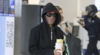 Guess who! International pop star goes incognito at Sydney Airport as she covers up in a long coat, face mask and sunglasses