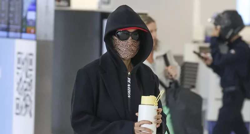 Guess who! International pop star goes incognito at Sydney Airport as she covers up in a long coat, face mask and sunglasses