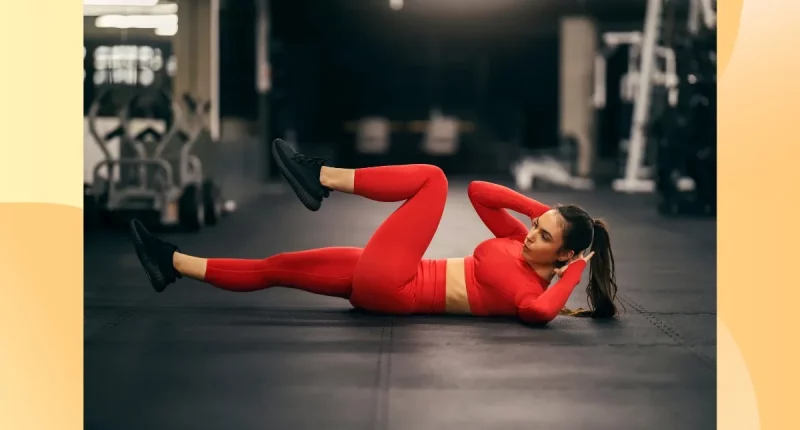 fit woman in red athletic attire doing bicycle crunches at the gym