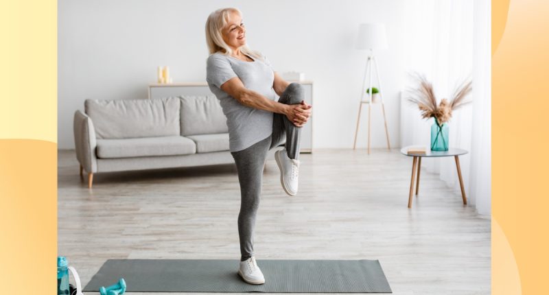 mature woman doing a single-leg balance exercise in bright living space