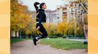 fit brunette woman doing jump rope workout outdoors on autumn day
