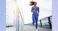 fit brunette woman running outdoors on bridge on fall or winter day