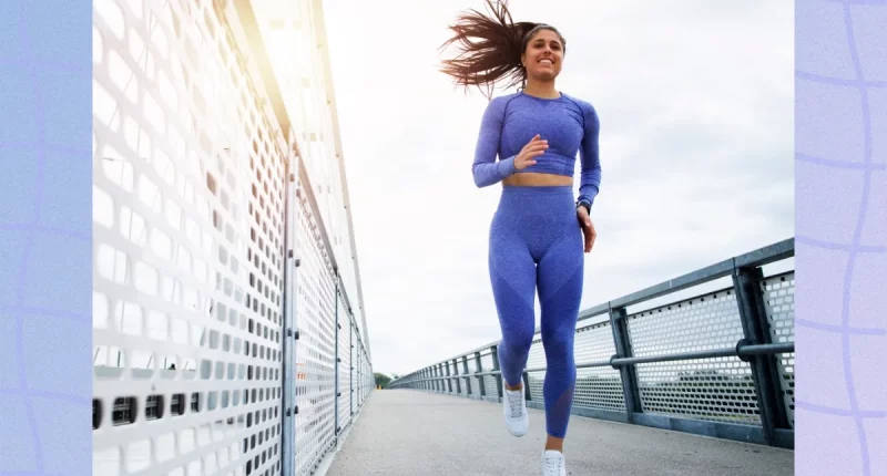 fit brunette woman running outdoors on bridge on fall or winter day