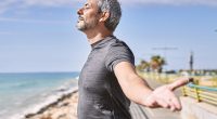 Middle age hispanic man wearing sportswear breathing at seaside