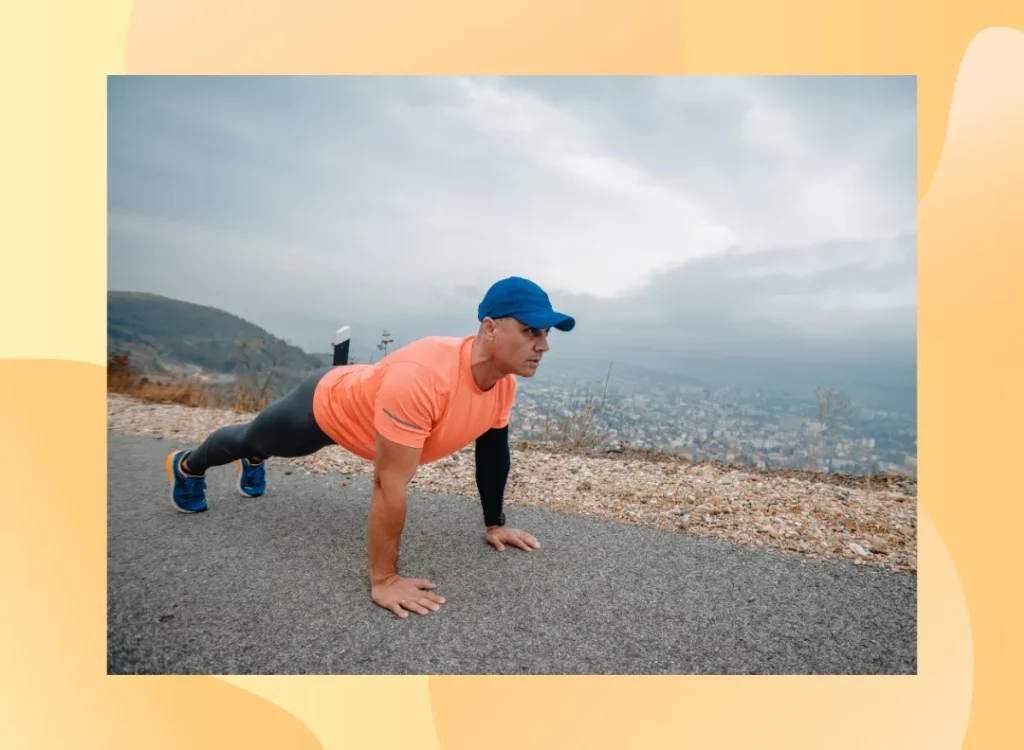 fit, mature man doing high plank or pushups on side of the road with mountains in the background