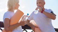 lderly couple discussing their yoga practice, drinking from water bottles