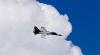 F-CK-1 fighter jet flying against a blue sky with clouds.
