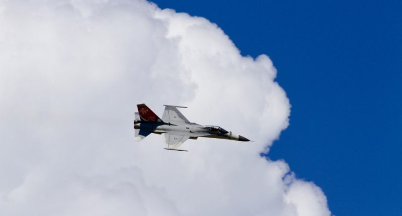 F-CK-1 fighter jet flying against a blue sky with clouds.