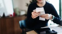 Woman reviewing receipts and using a digital tablet to manage her finances.