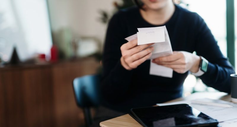 Woman reviewing receipts and using a digital tablet to manage her finances.