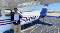 Pilot holding his certificate in front of a small airplane.