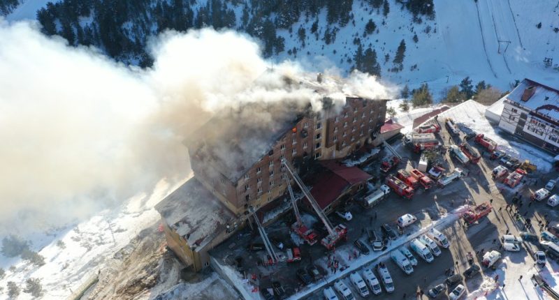 Aerial view of a hotel fire with fire trucks and ambulances responding.