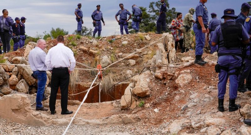 Police officers and private security personnel at a collapsed gold mineshaft.