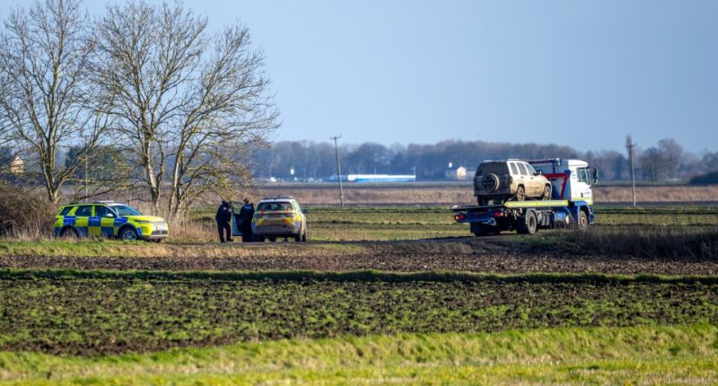 Police towing a vehicle away in a field.