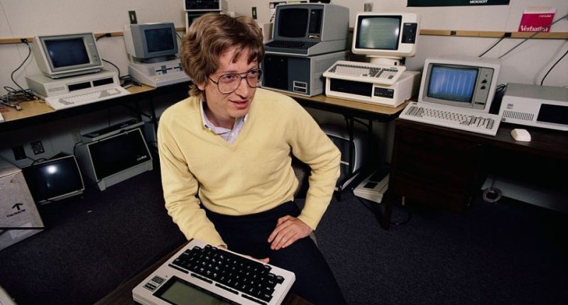 Bill Gates sitting at a desk among many computers.