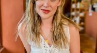 Woman with long blonde hair wearing a white crocheted top.