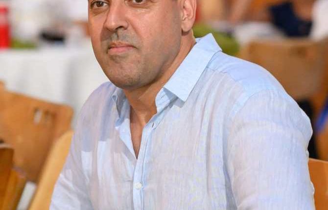 a man in a light blue shirt has sunglasses on his head