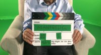 Holocaust survivor Manfred Goldberg holding a clapperboard.