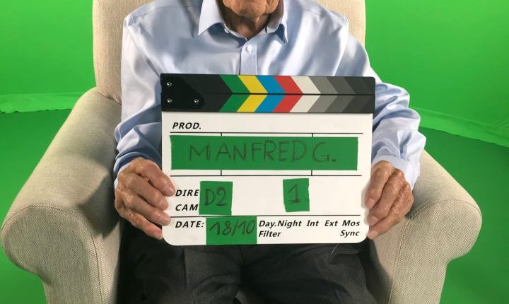 Holocaust survivor Manfred Goldberg holding a clapperboard.