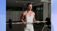 muscular man doing barbell curl in dark gym setting