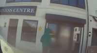 Person in a green hooded jacket standing outside a business center.