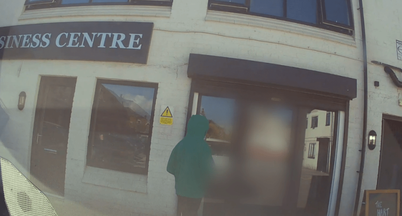 Person in a green hooded jacket standing outside a business center.