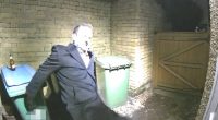 Man leaning against a bin, holding a bottle.