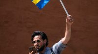 Man holding a Swedish flag and megaphone, using a phone.