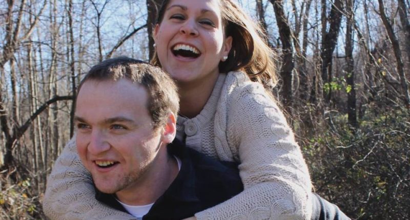 A woman piggybacking a man in a wooded area.