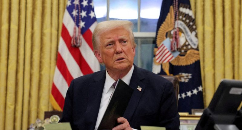 President Donald Trump in the Oval Office reviewing documents.