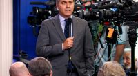CNN correspondent Jim Acosta speaking into a microphone at a press briefing.