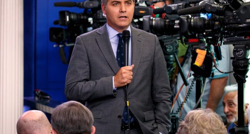 CNN correspondent Jim Acosta speaking into a microphone at a press briefing.
