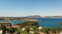 Overlooking the Gulf of Pozzuoli, boats are in the bay near Punta Pennata rocks.