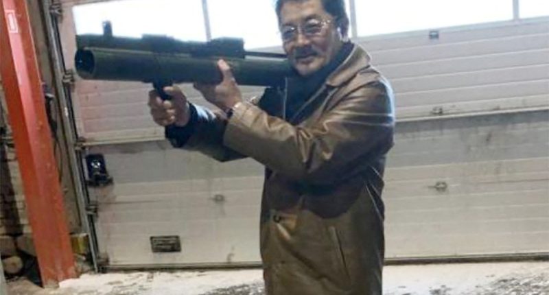 Man holding a rocket launcher in a warehouse.
