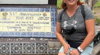 Woman sitting by a plaque commemorating the 15th anniversary of Dolores Hidalgo being named a Pueblo Mágico.