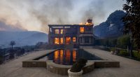 A palatial home on a hillside continues to burn in Pacific Palisades, Los Angeles
