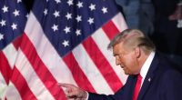 Former President Trump pointing in front of American flags.