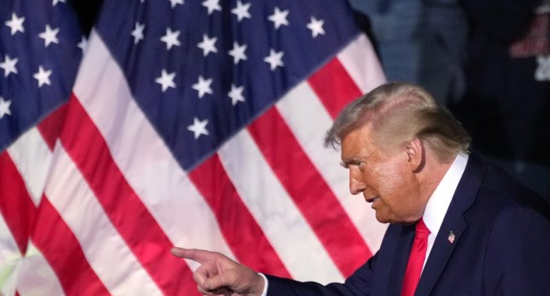 Former President Trump pointing in front of American flags.
