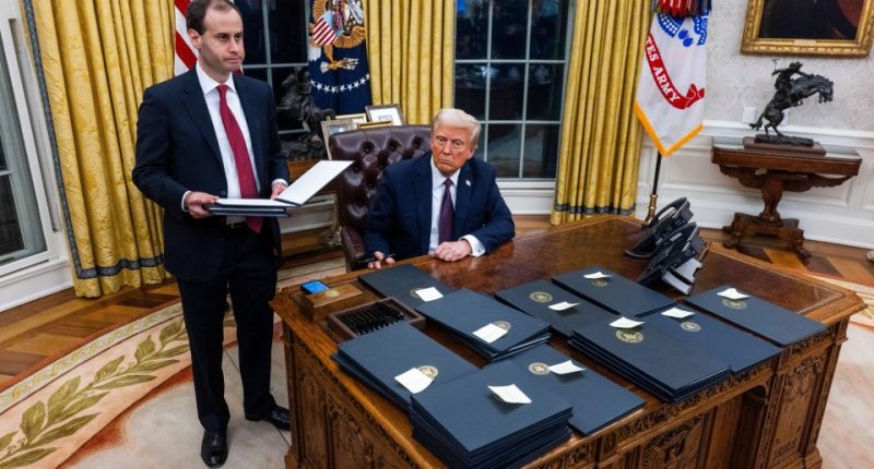 President Trump signing executive orders in the Oval Office.