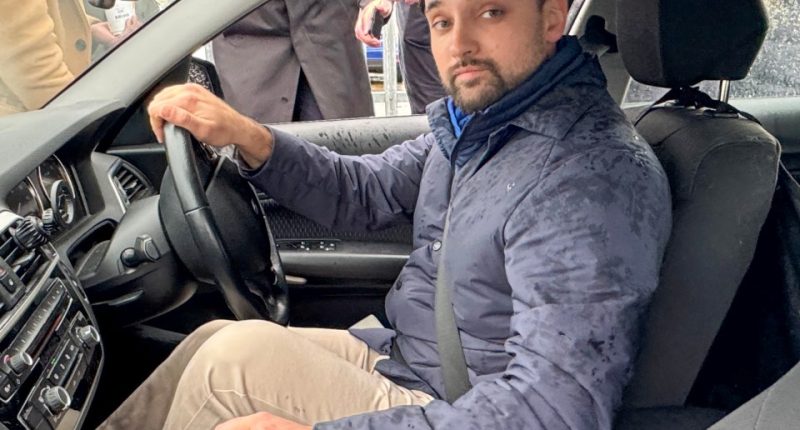 Man with bandaged finger sitting in a car.