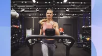 fit woman running on the treadmill in dark gym set-up