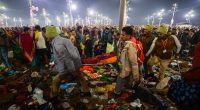 People carrying an injured person through debris at the Kumbh Mela.