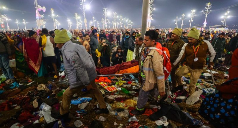 People carrying an injured person through debris at the Kumbh Mela.