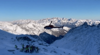 Helicopter over snowy mountains and rescue team.
