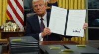 President Trump holding a signed executive order commuting sentences for January 6th offenses.