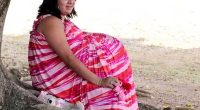 Woman in pink and red striped dress pretending to be pregnant.